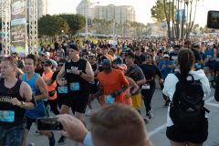 10/13/2019 – LONG BEACH, CALIF: Peter Emelue, 60 (orange shirt and yellow hat), smiles at the start of his run in the Long Beach Half Marathon. Photograph by Dillon Hulse.