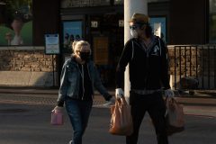 Two shoppers share conversation through the required face coverings as they exit the Ralphs grocery store at the traffic circle in Long Beach Monday, April 20, 2020. Photograph by Dillon Hulse.